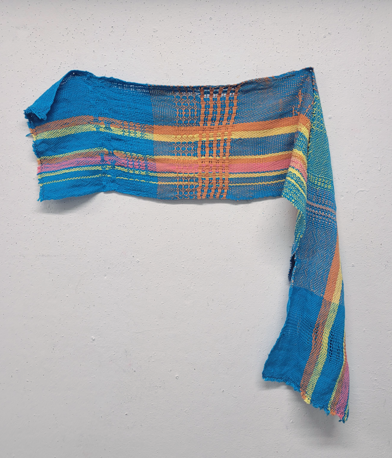 blue backstrap weaving with pink, orange, and yellow stripes